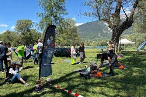 Activité découverte du tir à la carabine organisée par le comité de sport adapté. Des sportifs sont allongés dans l'herbe, par une belle journée d'été, dans les Hautes-Alpes, avec une montagne en fond.