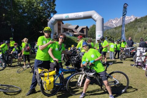 Photos de sportifs pendant la Traversée des Hautes-Alpes, en 2024, organisée par le Comité départemental de sport adapté. Les sportifs sont souriants, en t-shirt vert fluo, avec un vélo, devant l'arche d'arrivée, sous un beau ciel bleu.