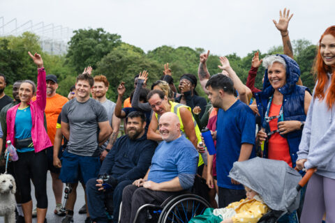 Groupe de sportifs de tous âges, valides ou en situation de handicap, souriants. Ils posent ensemble avant une course en extérieur