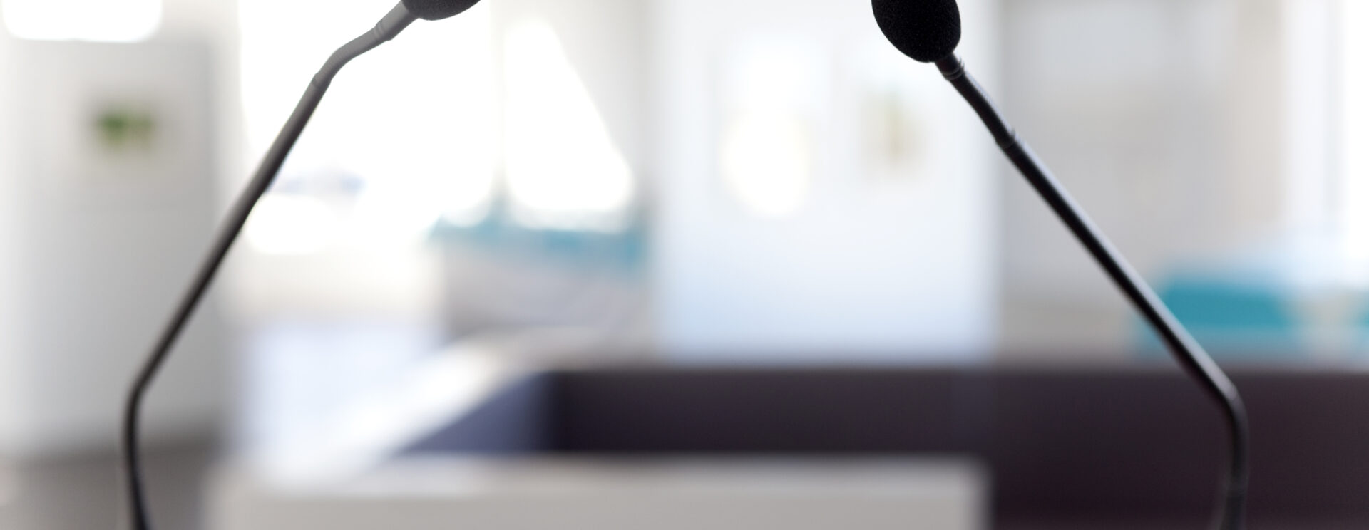 Au premier plan, un pupitre équipé de deux micros, en arrière-plan une salle.